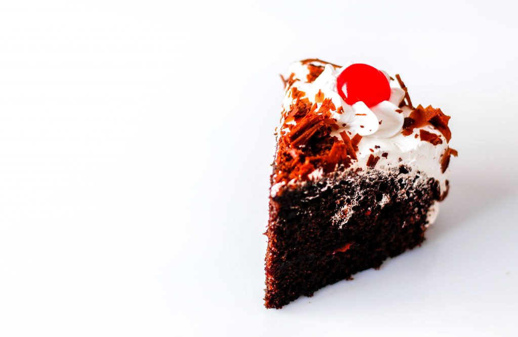chocolate cake with a cherry and whipped topping.