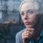Sad woman looking out of a rain-soaked window