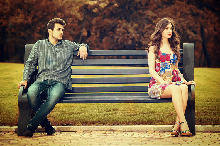 Young woman ignoring a man looking at her on a park bench