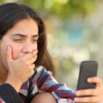 worried teenager looking at her mobile phone