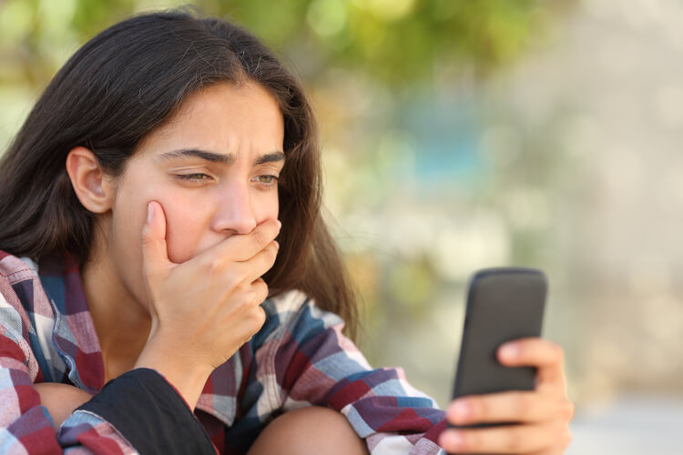 worried teenager looking at her mobile phone