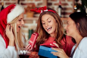 Three female friends swapping Christmas gifts
