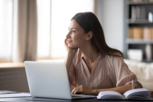 woman thinking happy thoughts while working at her laptop