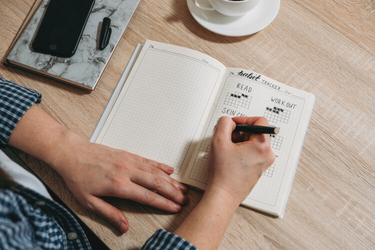 man filling in a habit tracker in his bullet journal