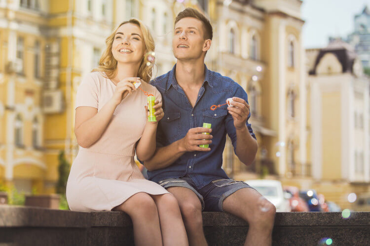 couple blowing bubbles in a city setting