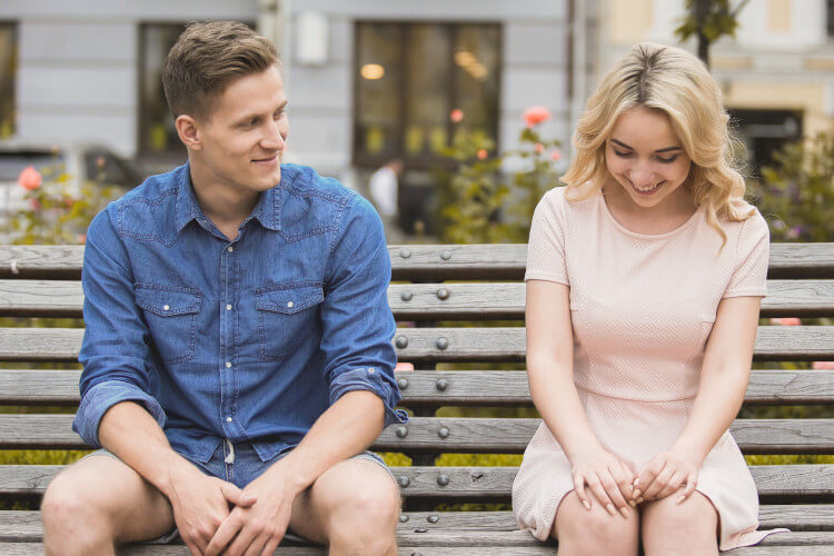 man smiling at woman on bench